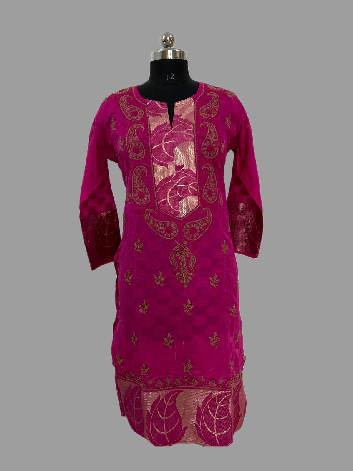 A magenta pink kurta with gold metallic embroidery, displayed on a black dress form mannequin against a solid gray background.