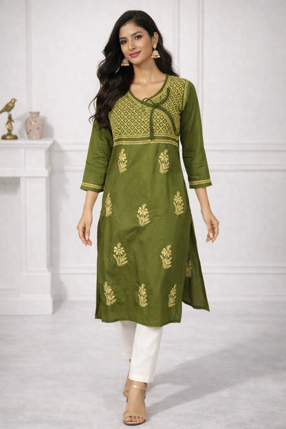 A woman models an olive green Indian kurta with gold embroidery, paired with white pants and beige sandals, in a bright indoor setting.