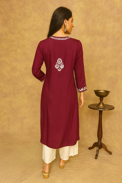 Woman wearing a maroon kurta with white embroidery on a beige background