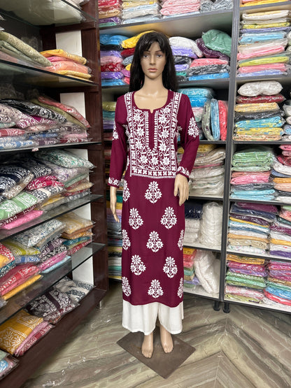 Mannequin wearing a maroon dress with white patterns in a fabric store.