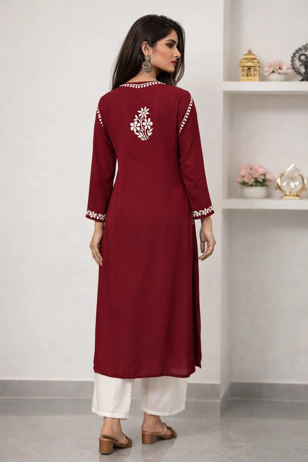 Woman wearing a maroon kurta with white embroidery in a minimalistic room.