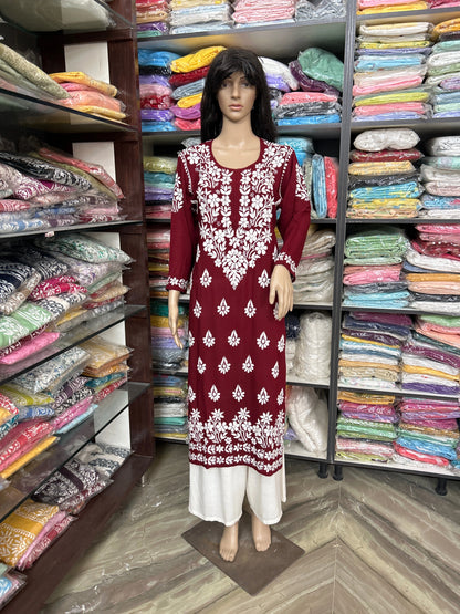 Lucknowi Chikankari Mannequin wearing a red and white dress in a fabric store with shelves of colorful fabrics.