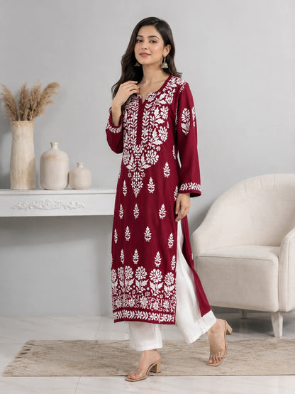 Woman wearing a maroon and white embroidered kurta in a minimalistic room.