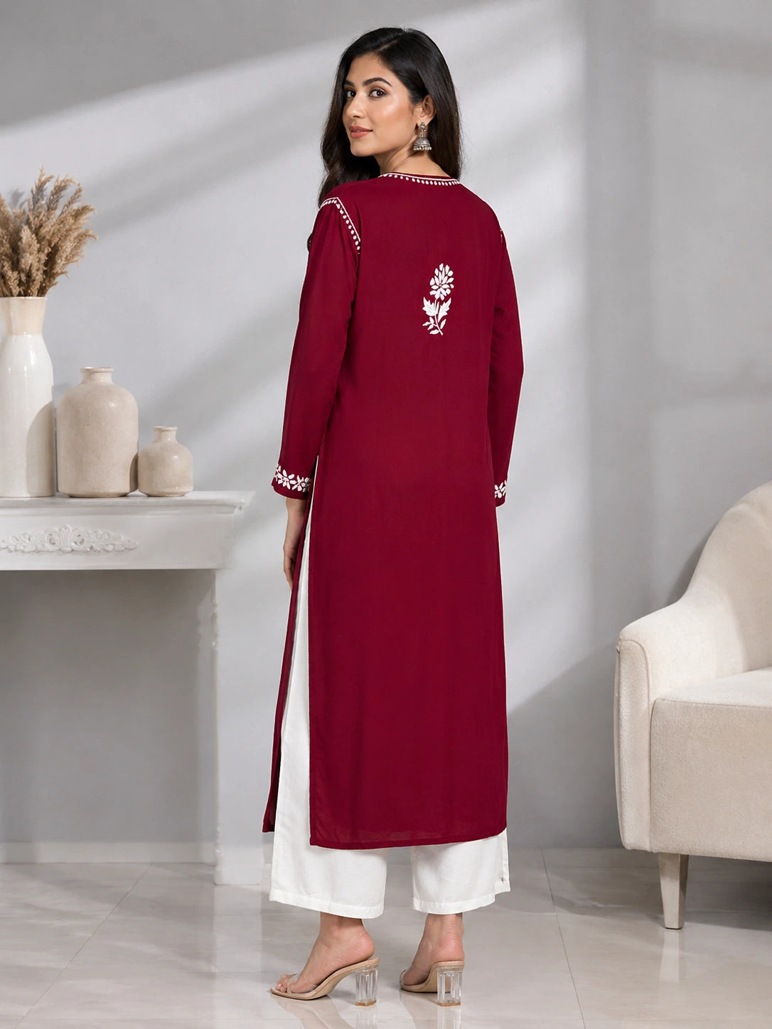 Lucknowi chikankari Woman wearing a maroon and white traditional outfit in a minimalistic room.
