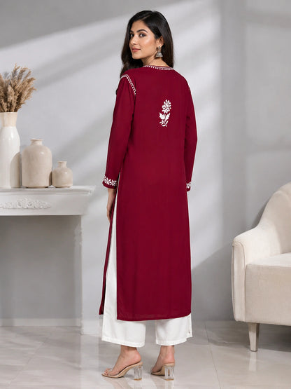 Lucknowi chikankari Woman wearing a maroon and white traditional outfit in a minimalistic room.