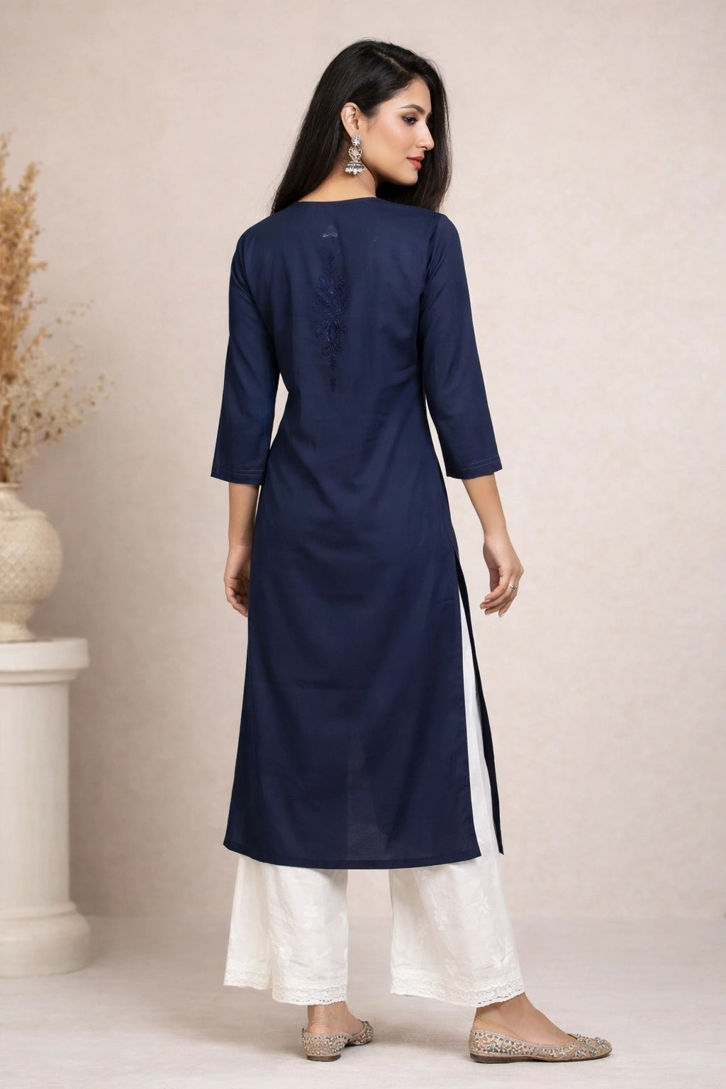 Lucknowi chikankari Woman wearing a navy blue kurta with white pants against a beige background