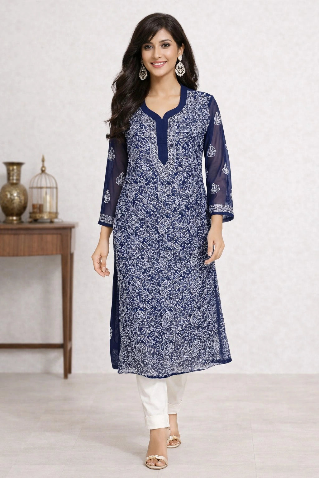 Lucknowi chikankari A woman modeling a navy blue and white printed kurta with white pants, standing in a studio setting with a decorative side table in the background.