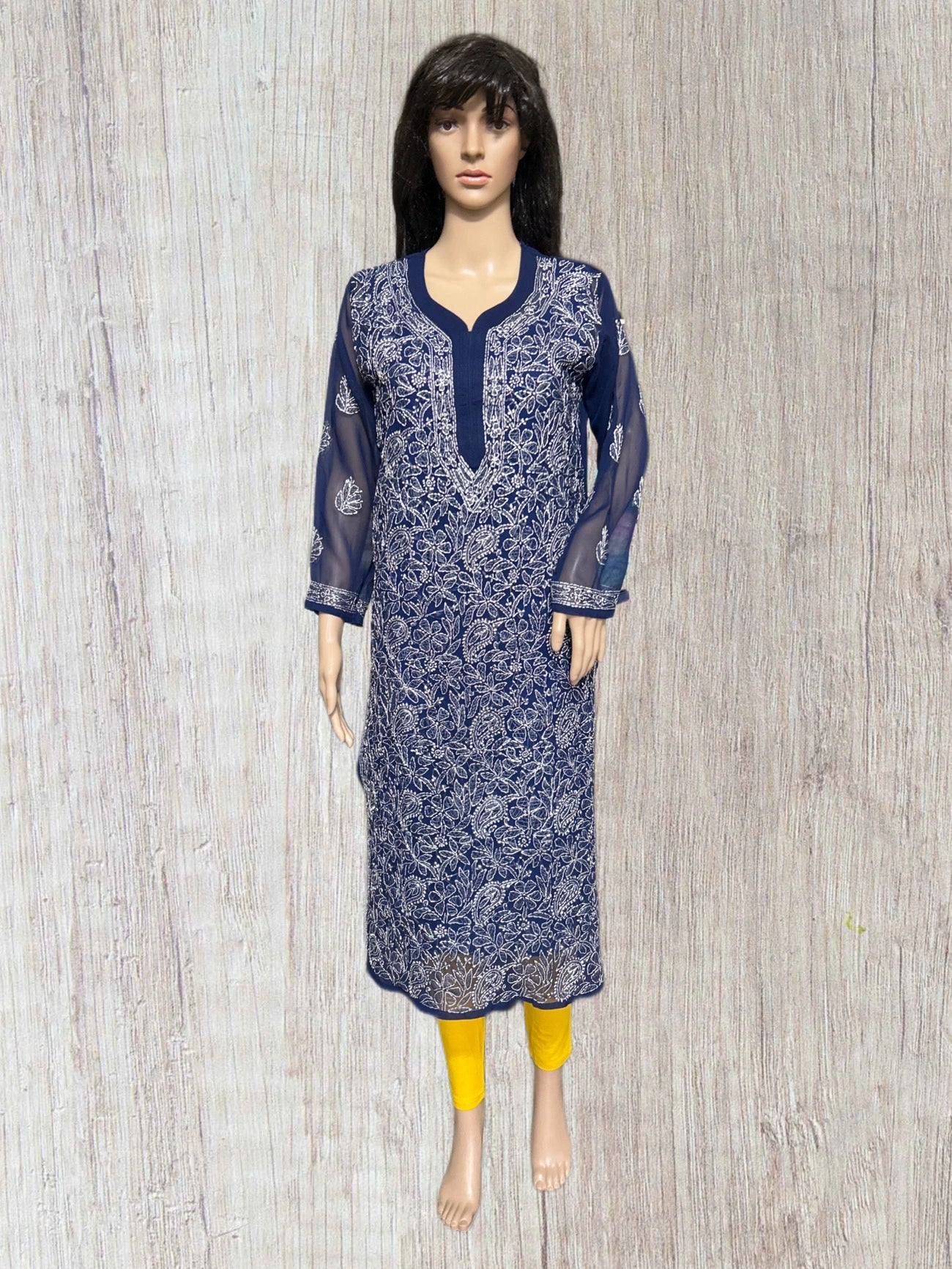 lucknowi chikankari A navy blue and white printed kurta displayed on a female mannequin, styled with yellow leggings, set against a light gray wood-textured background.