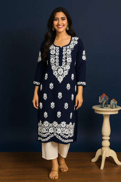 Woman wearing a navy blue kurta with white floral embroidery against a dark blue background.
