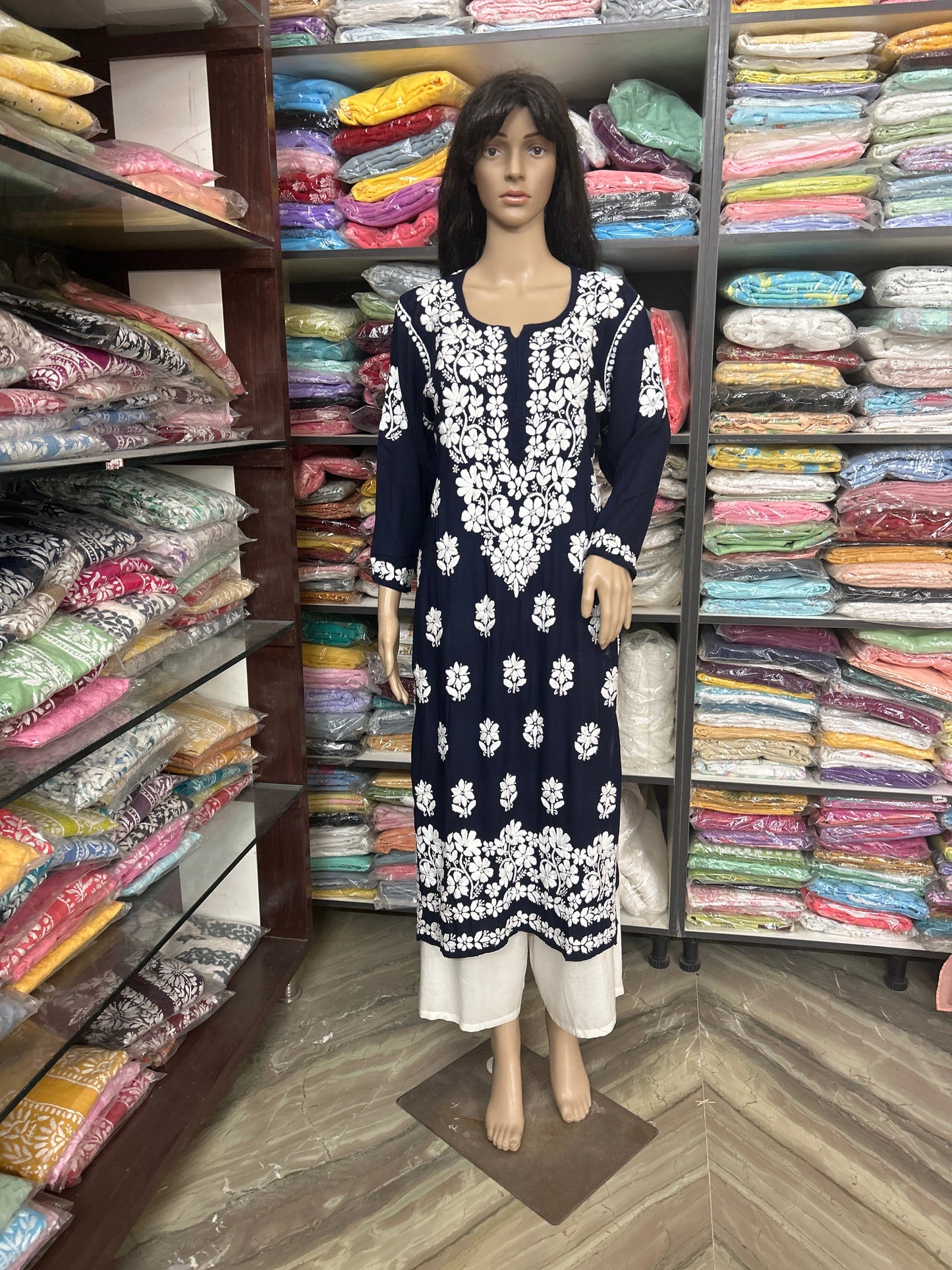 lucknowi chikankari Mannequin wearing a navy blue dress with white floral patterns in a fabric store.
