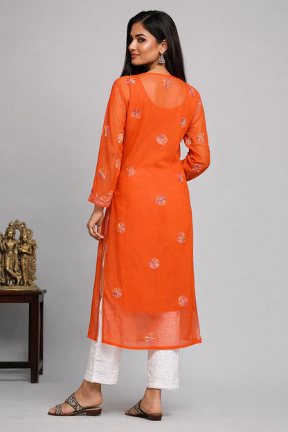 Woman wearing an orange kurta with white pants on a gray background