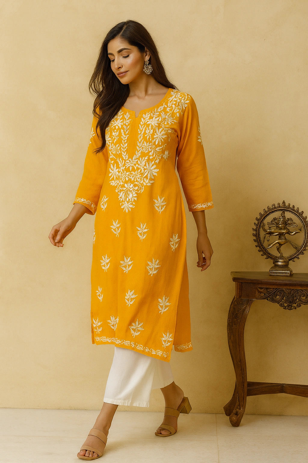 Woman wearing a yellow embroidered kurta with white pants against a beige background