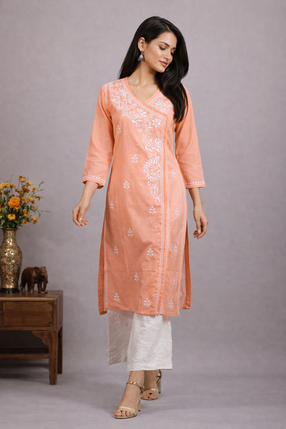 Woman wearing a peach kurta with white pants against a gray background