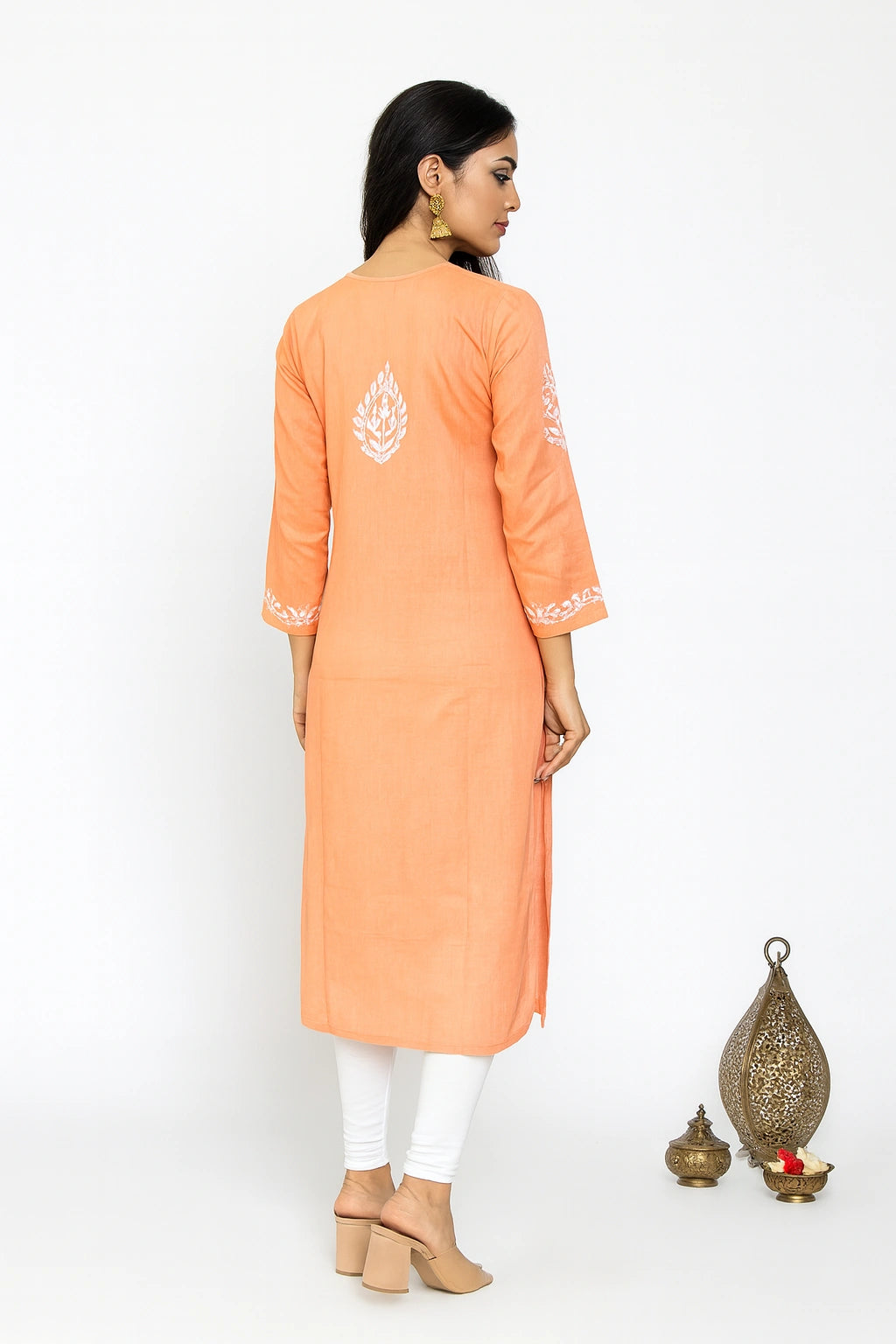 women wearing a lucknowi chikankari Peach embroidered dress  against a gray background