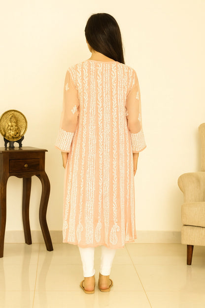 Woman wearing a peach-colored embroidered kurta in a minimalistic room.