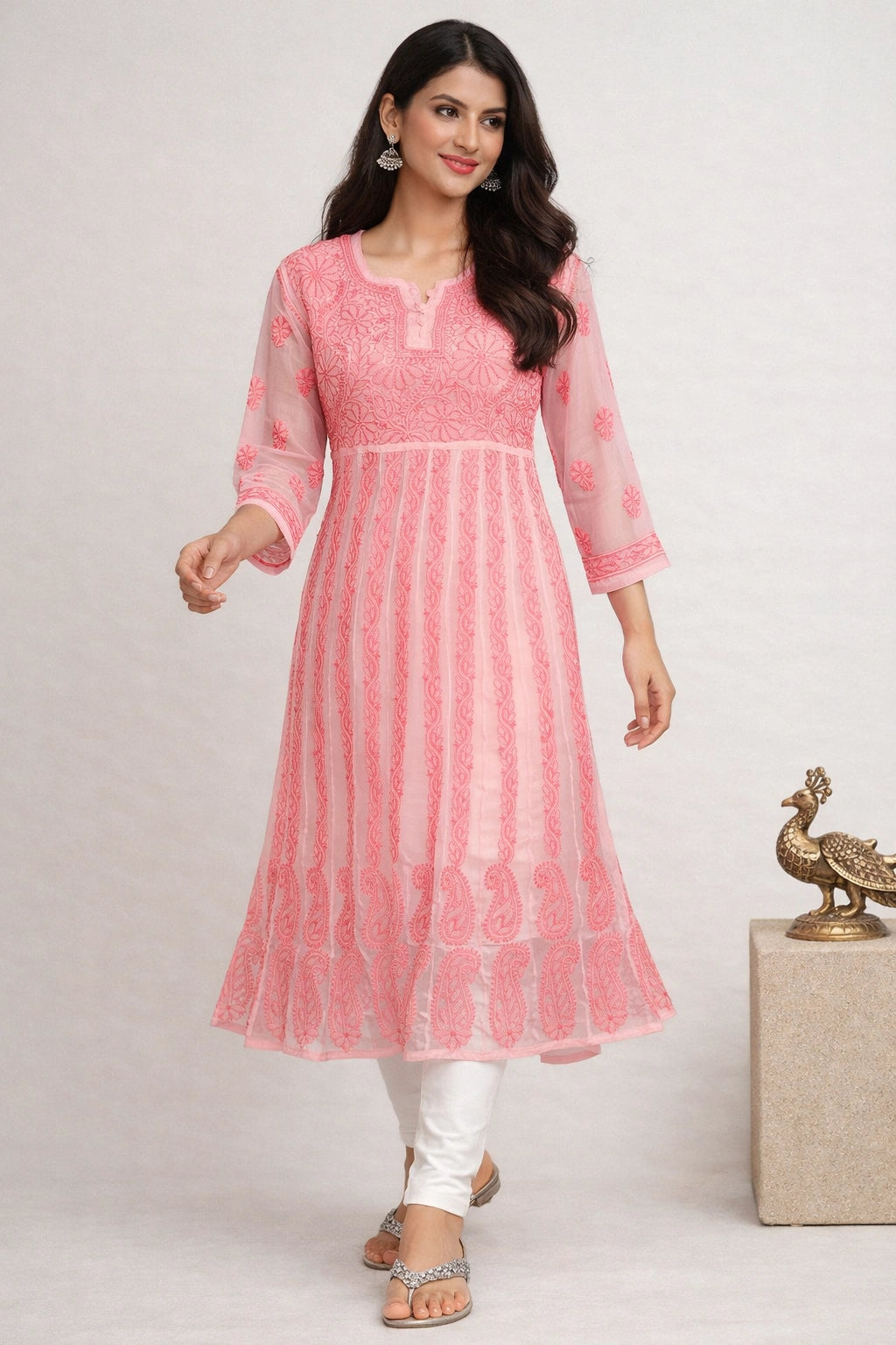 Woman wearing a pink traditional outfit with white pants on a light gray background