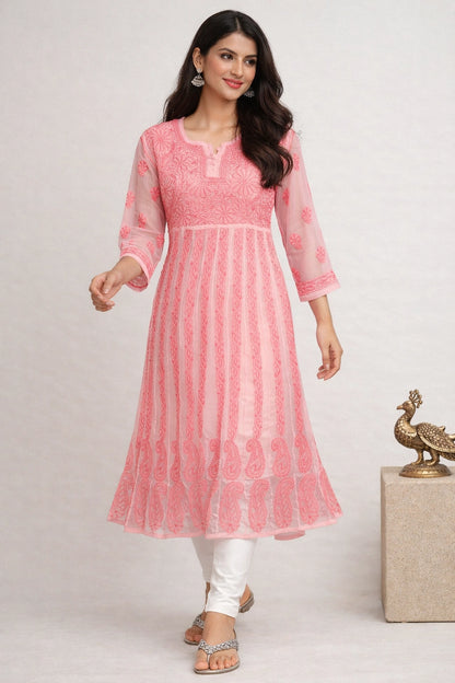 Woman wearing a pink traditional outfit with white pants on a light gray background
