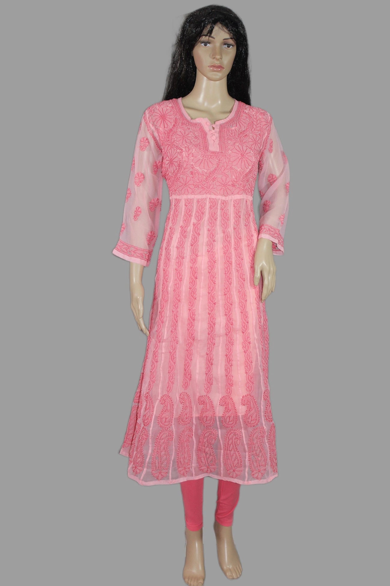 Woman wearing a chikan pink traditional outfit with white pants in a decorated room.