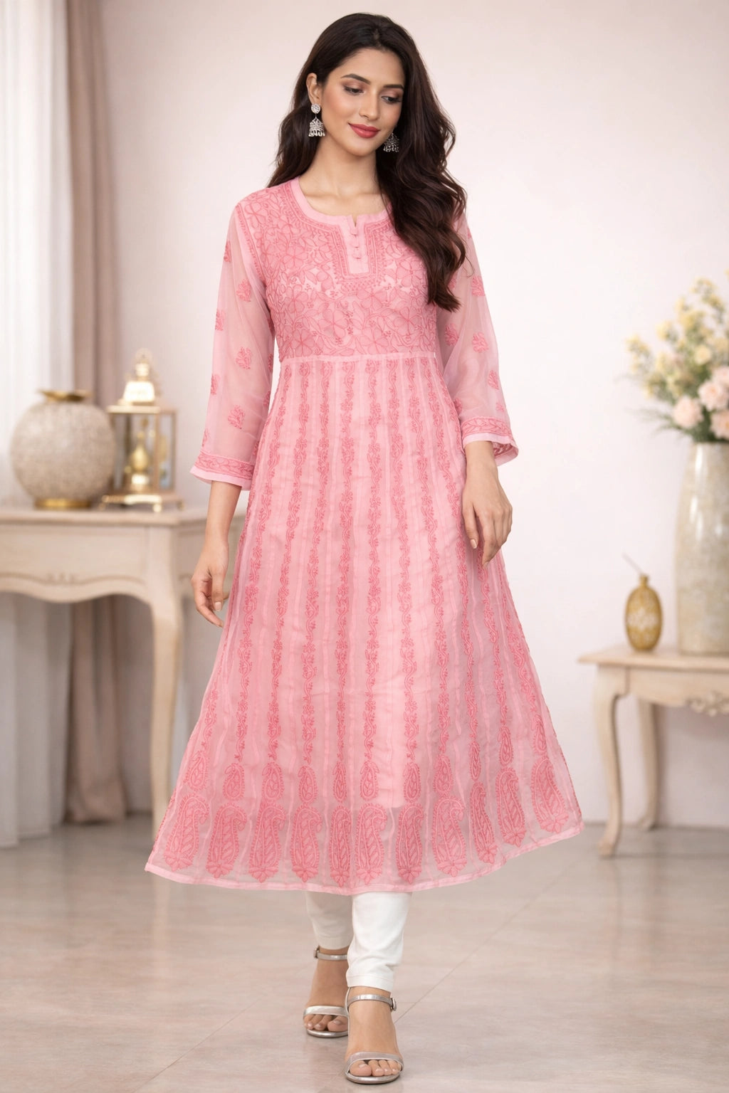 Woman wearing a chikan pink traditional outfit with white pants in a decorated room.