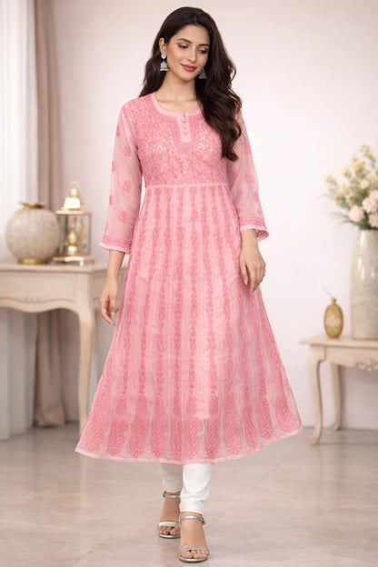Woman wearing a chikan pink traditional outfit with white pants in a decorated room.