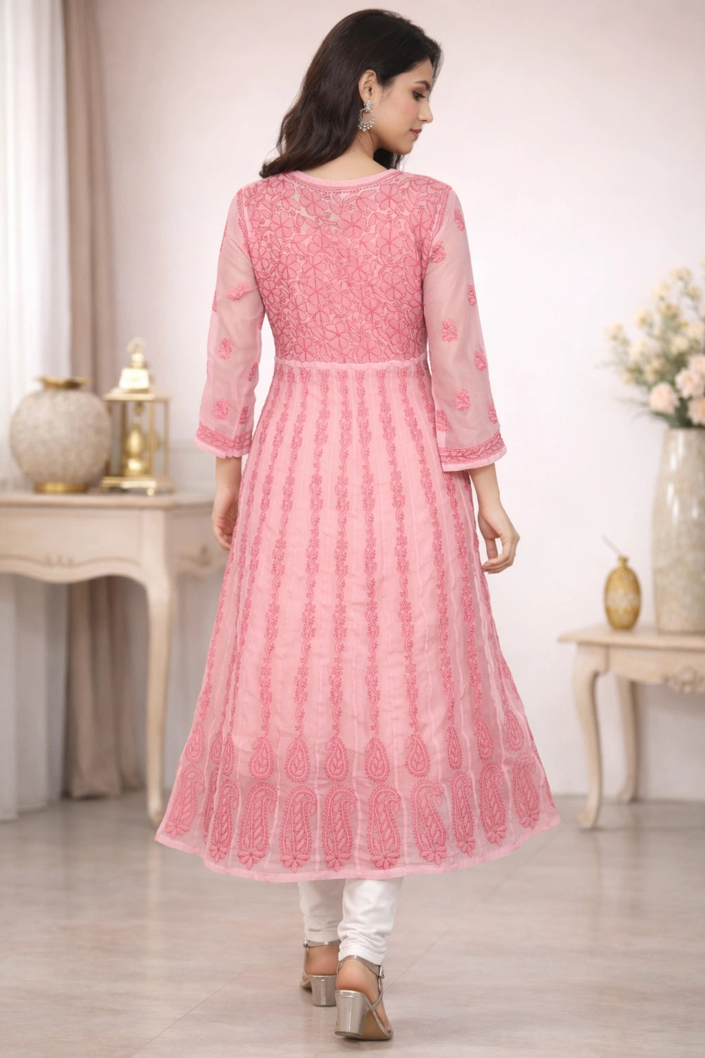 Woman wearing a lucknowi chikankari pink traditional outfit in a room with decorative elements.