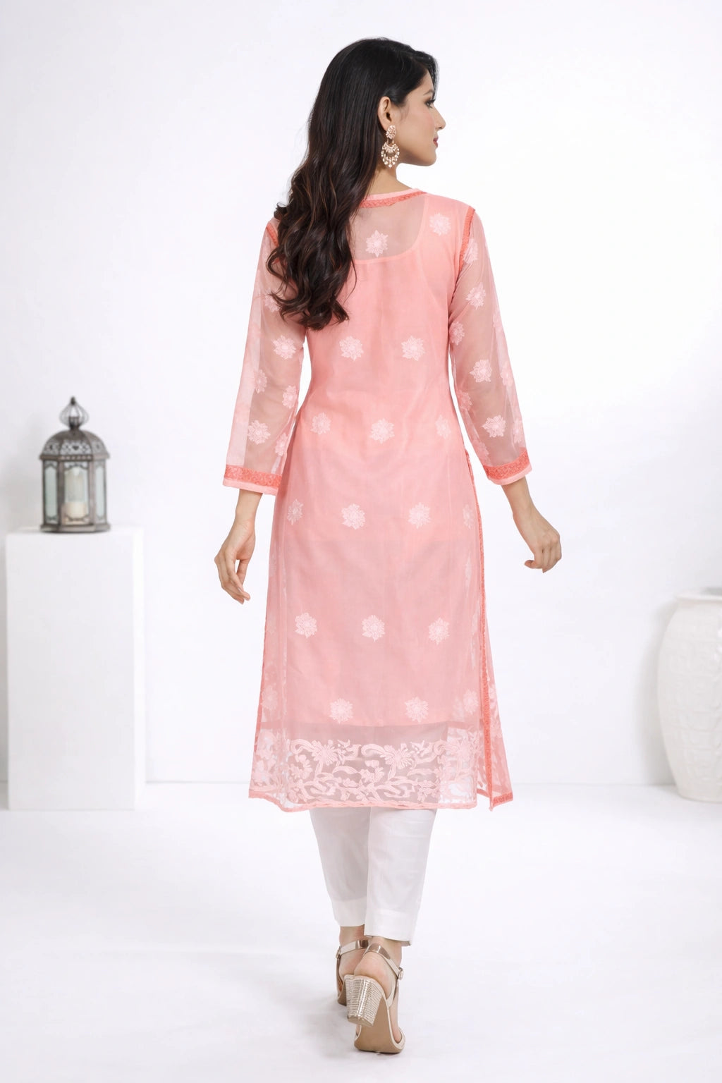 Woman wearing a pink kurta with white patterns on a white background