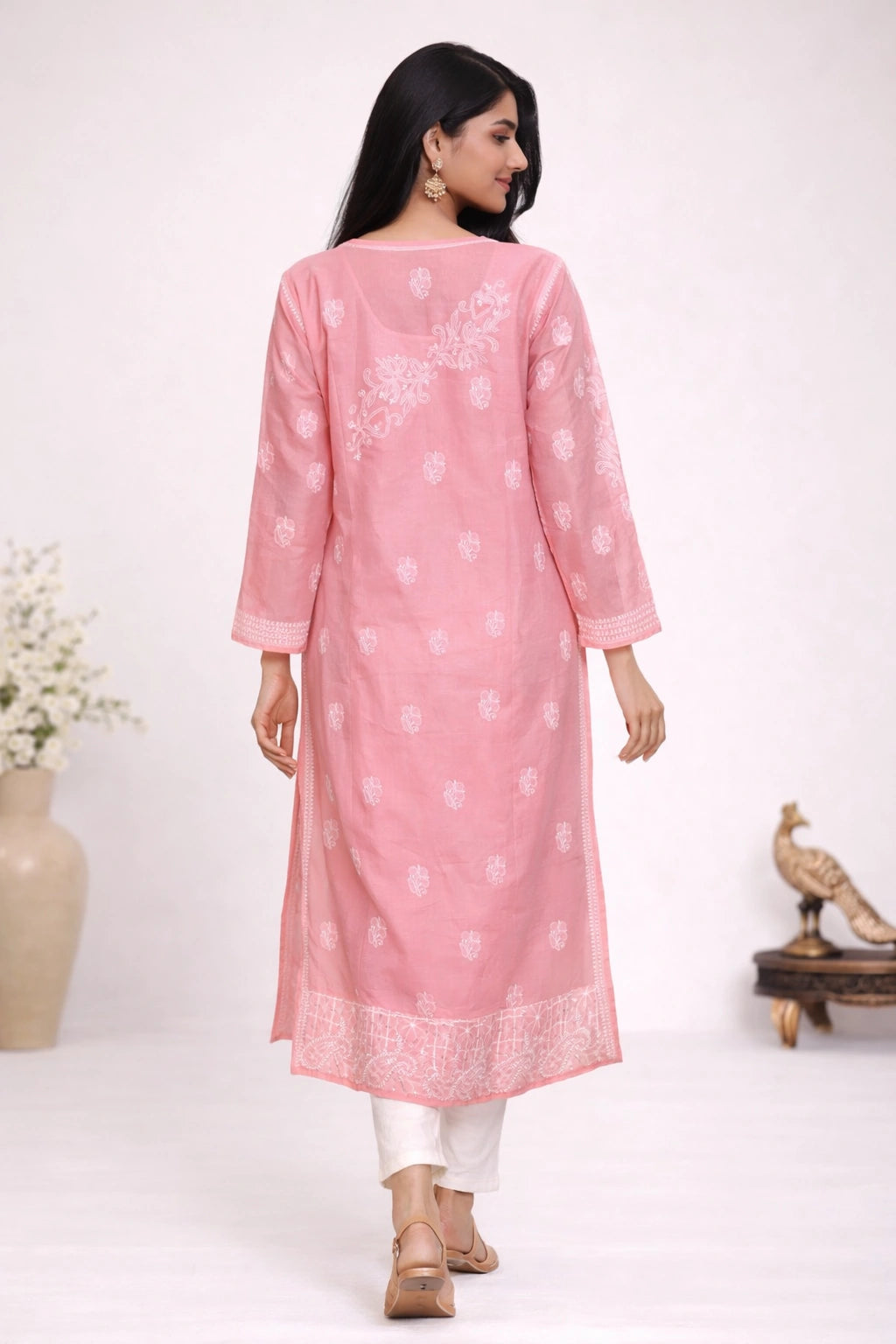 Woman wearing a pink kurta with white patterns on a white background