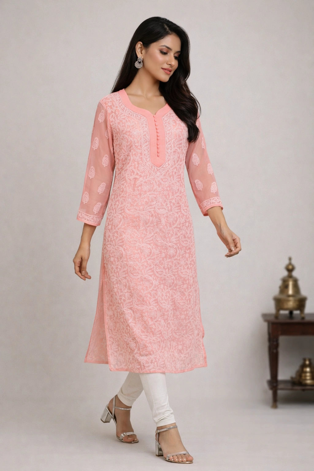 Woman wearing a pink kurta with white pants against a plain background