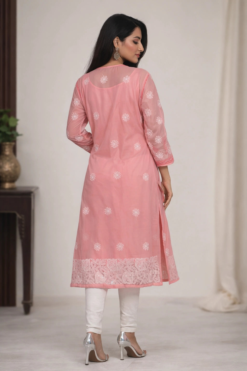 Woman wearing a pink kurta with white embroidery in a minimal indoor setting