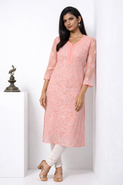 Woman wearing a pink kurta with white pants against a white background