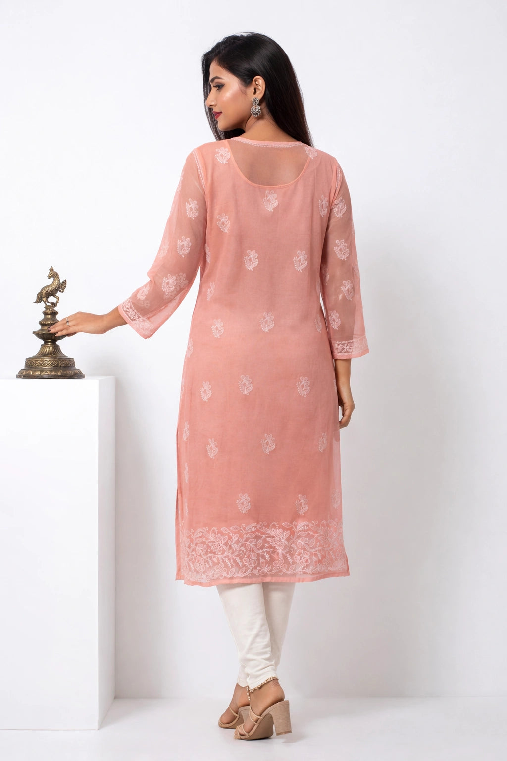 Woman wearing a pink kurta with white patterns on a white background