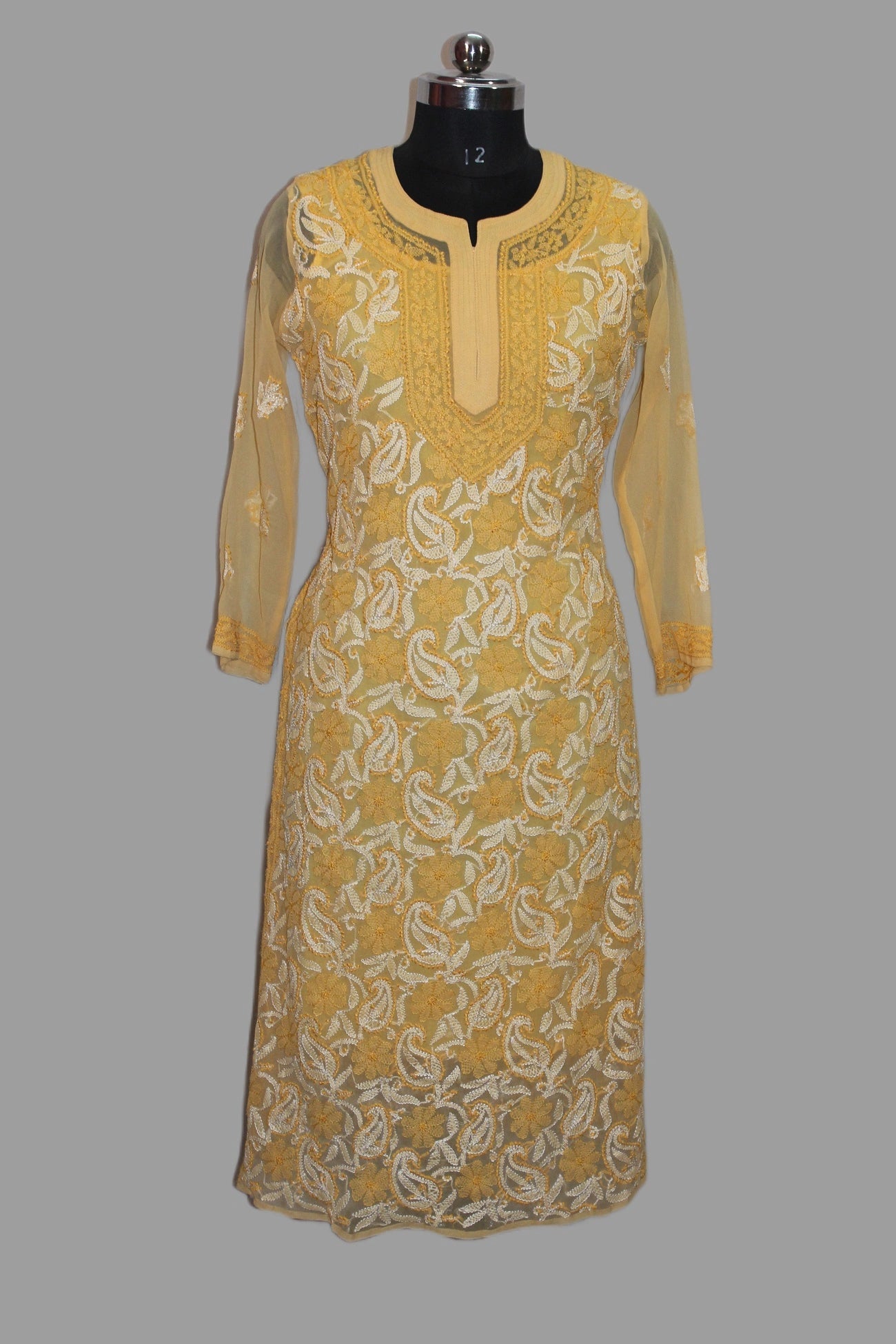 Yellow embroidered dress on a mannequin against a gray background