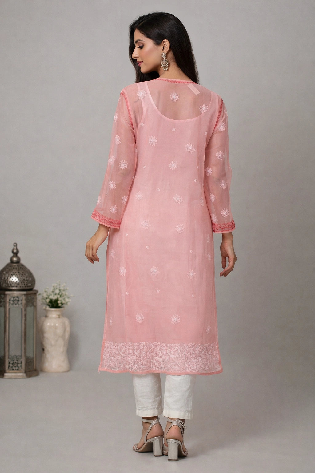 Woman wearing a pink kurta with white patterns on a gray background