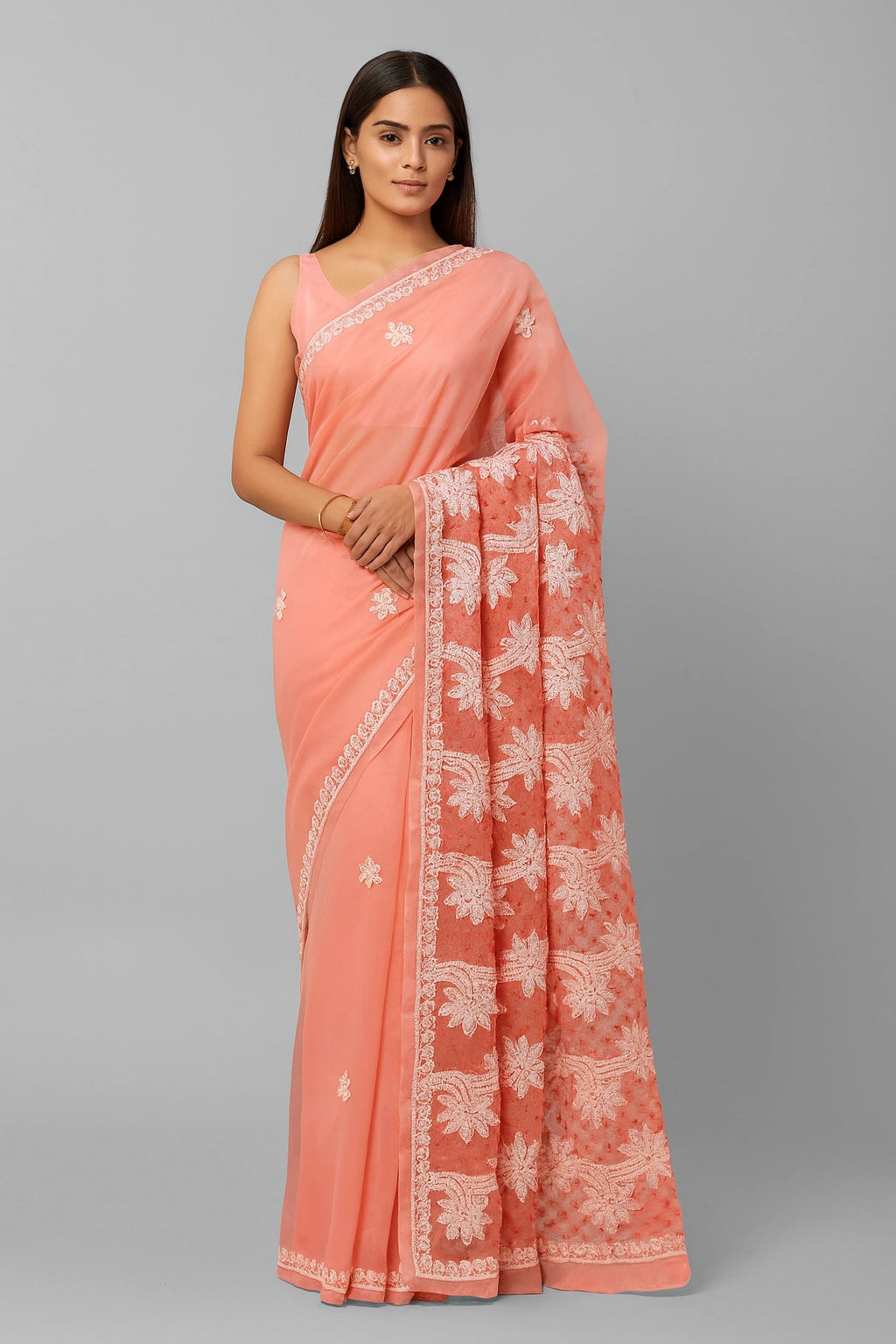Woman wearing a lucknowi chikankari peach saree with white floral patterns on a gray background