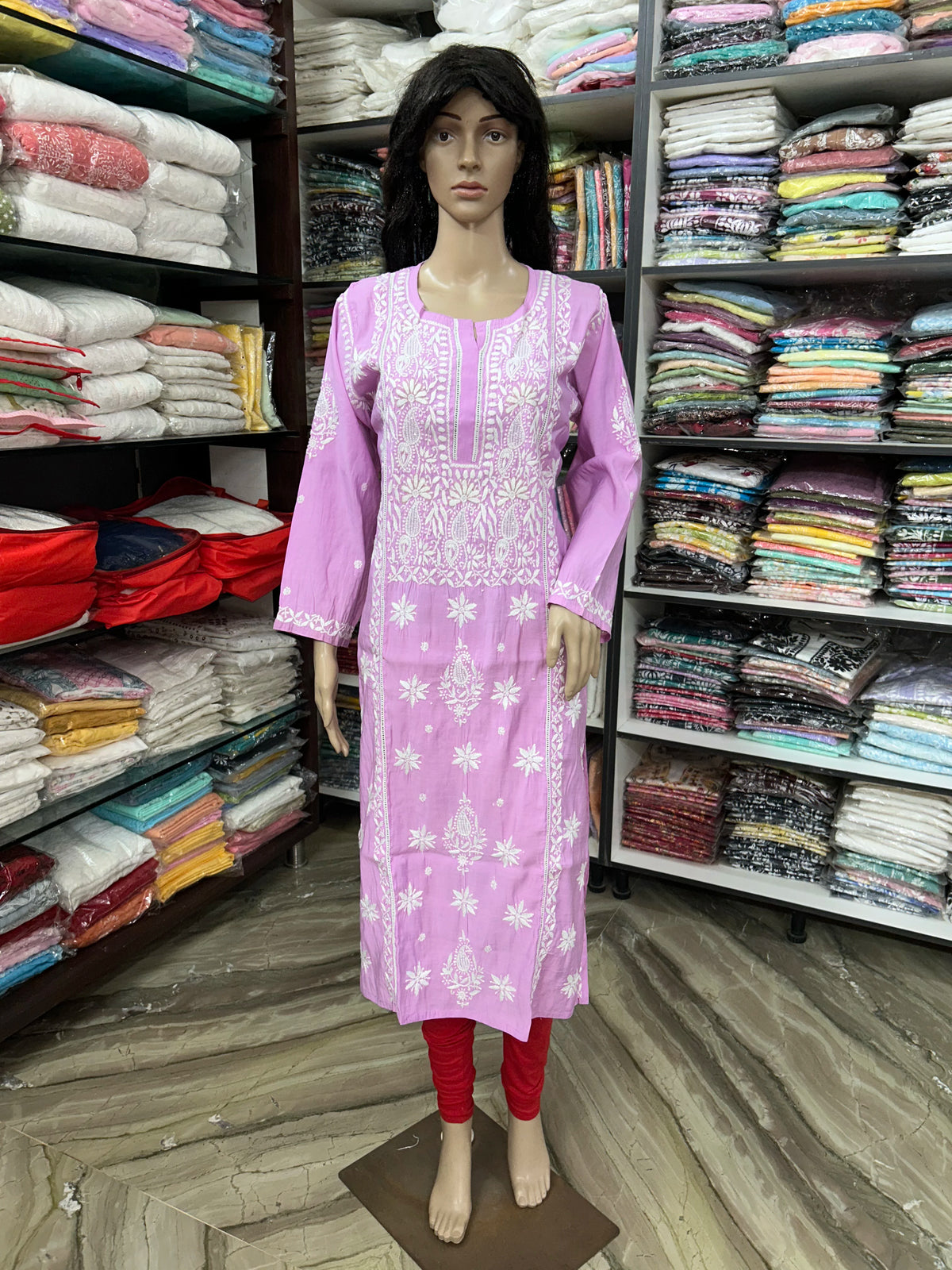 A white embroidered kurta with pink sleeves and red leggings displayed on a female mannequin in a clothing store.