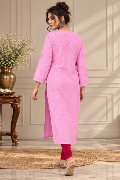 A woman wearing a pink three-quarter sleeve kurta with red leggings and beige flat shoes, shown from the back in an indoor setting with a decorative table and vase.