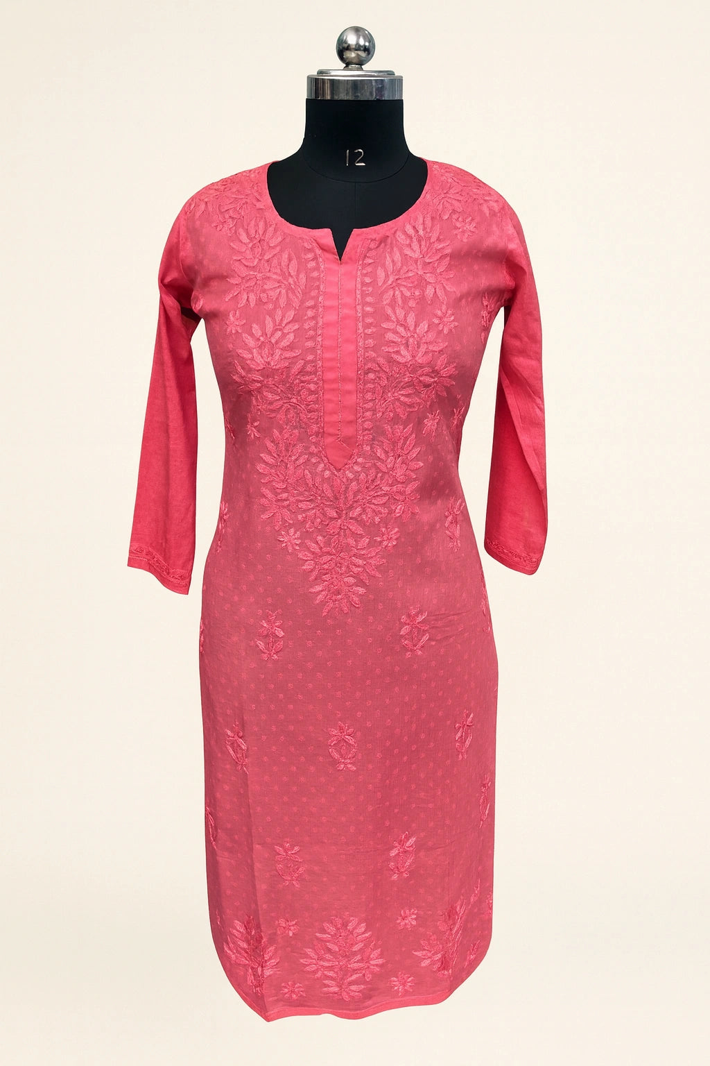 Pink dress with floral embroidery on a mannequin against a white background