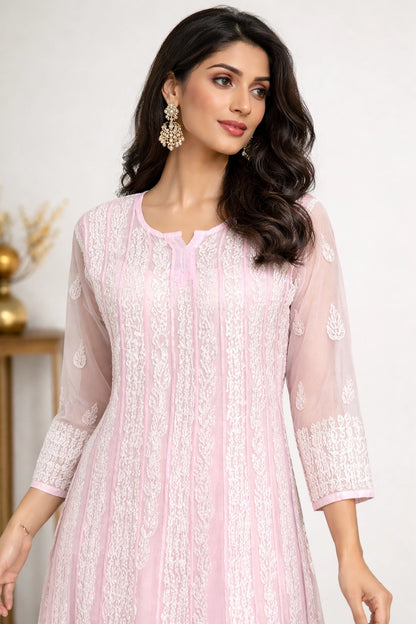 Woman wearing a light pink embroidered dress with a white background