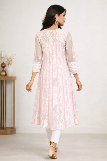Woman wearing a lucknowi chikankari light pink kurta with white pants against a plain background