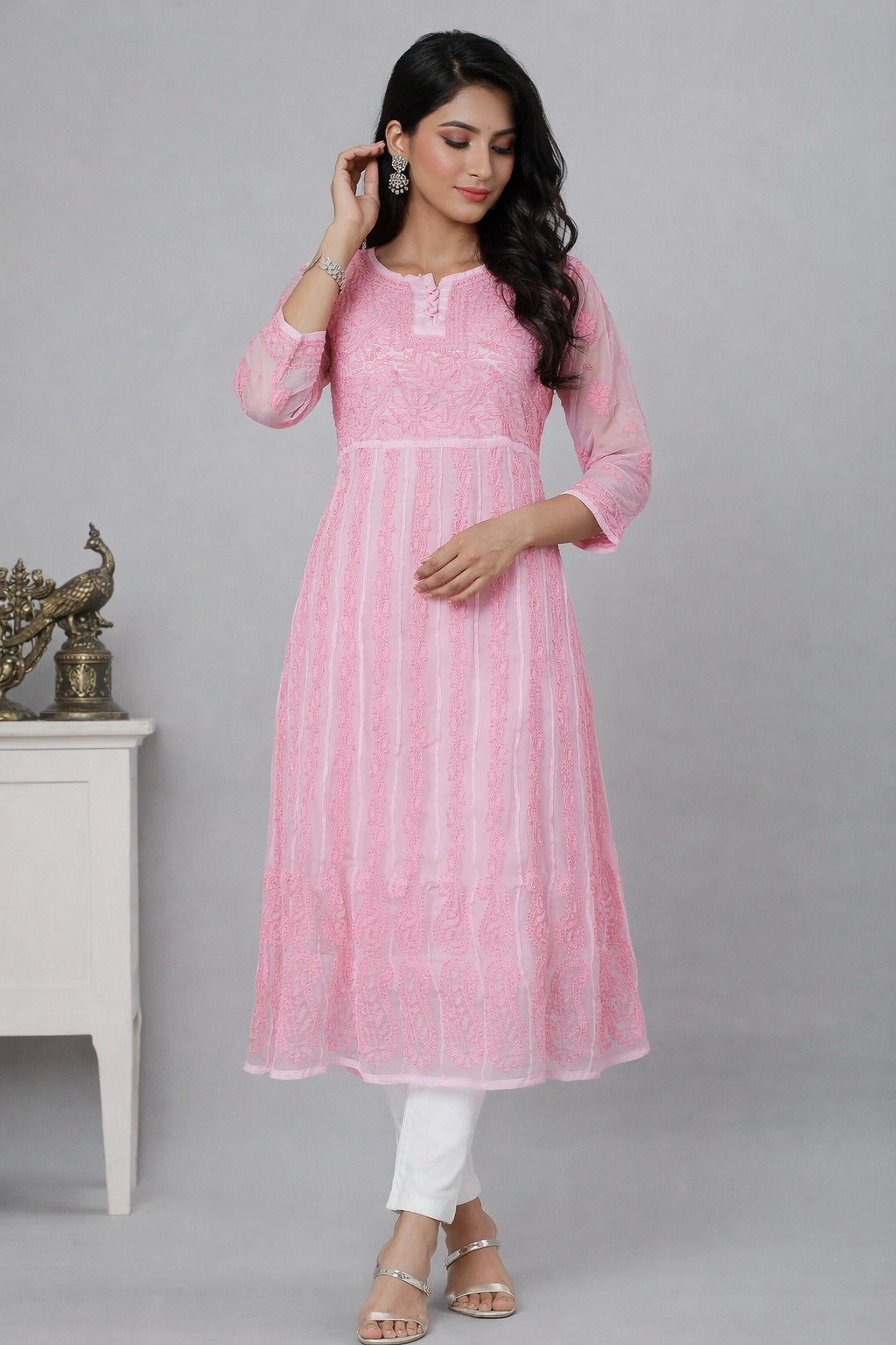 Woman wearing a chikan pink kurta with white pants against a gray background