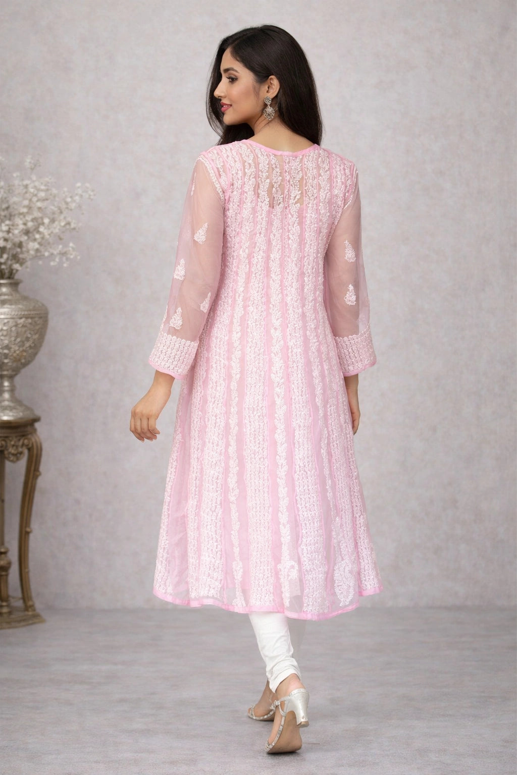 Woman wearing a chikankari pink traditional outfit with white patterns on a gray background