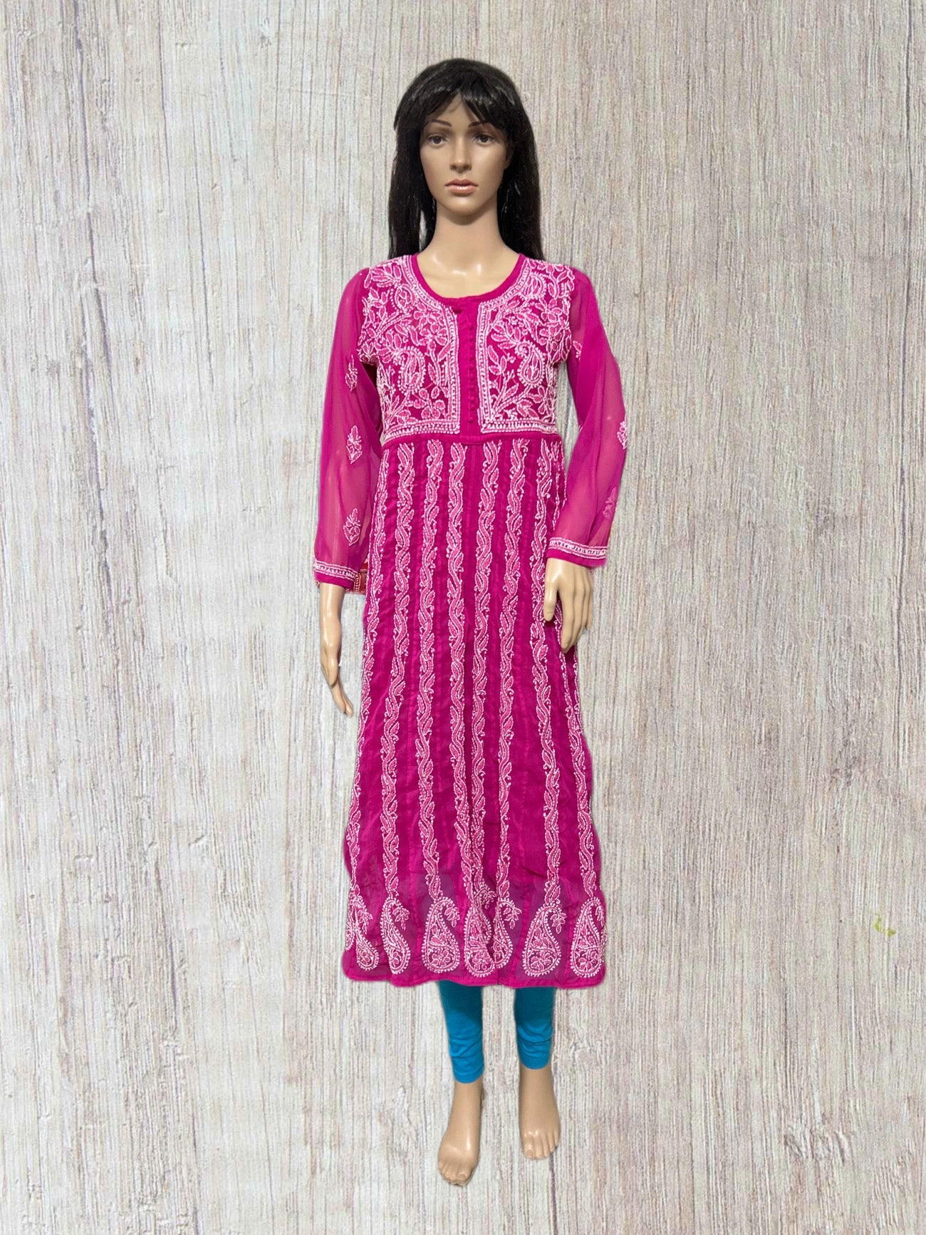 Mannequin wearing a pink embroidered dress on a wooden floor background
