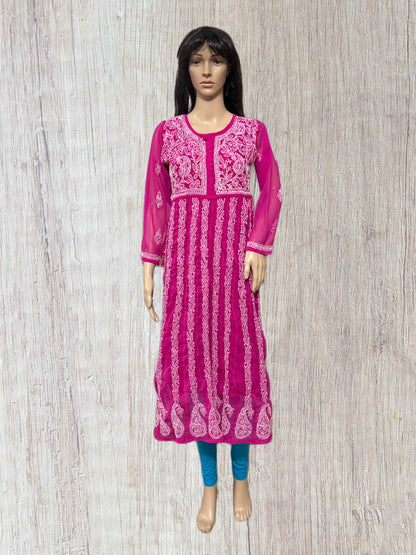 Mannequin wearing a pink embroidered dress on a wooden floor background
