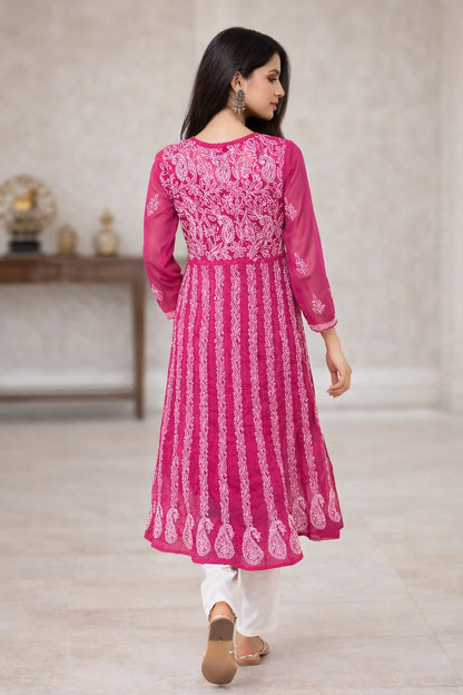 Woman wearing a pink and white embroidered traditional outfit in a neutral setting