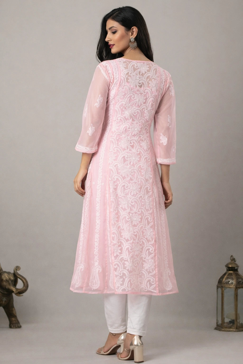 Woman wearing a pink embroidered kurta with white pants against a gray background