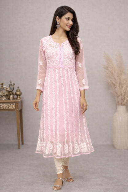 Woman wearing a pink embroidered kurta with white pants in a minimalistic setting.