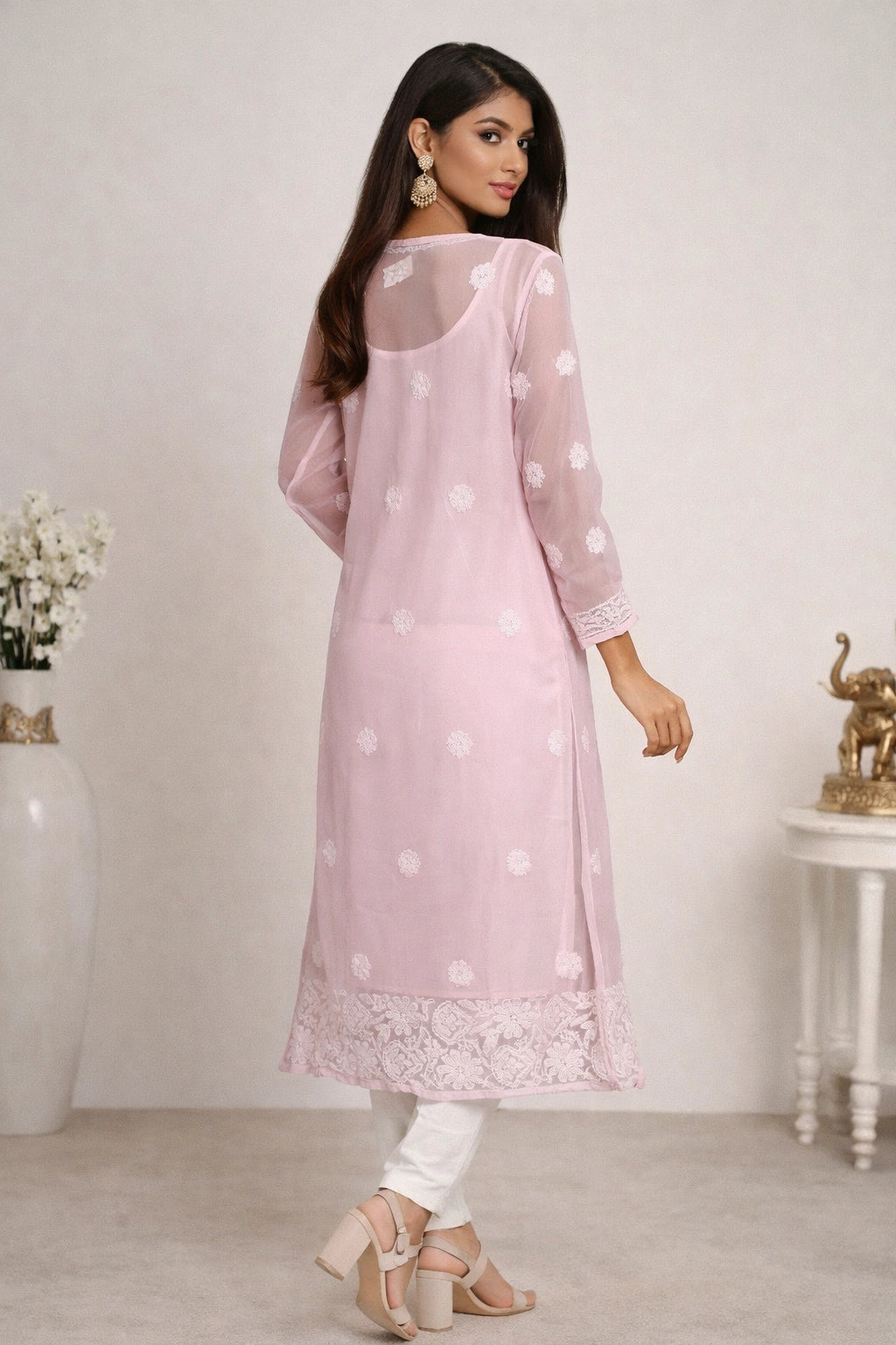 Woman wearing a lucknowi light pink kurta with white polka dots and lace details, standing against a plain background.