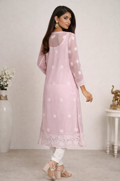Woman wearing a lucknowi light pink kurta with white polka dots and lace details, standing against a plain background.
