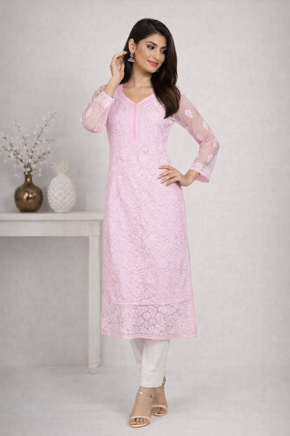 Woman wearing a pink embroidered kurta with white pants against a plain background
