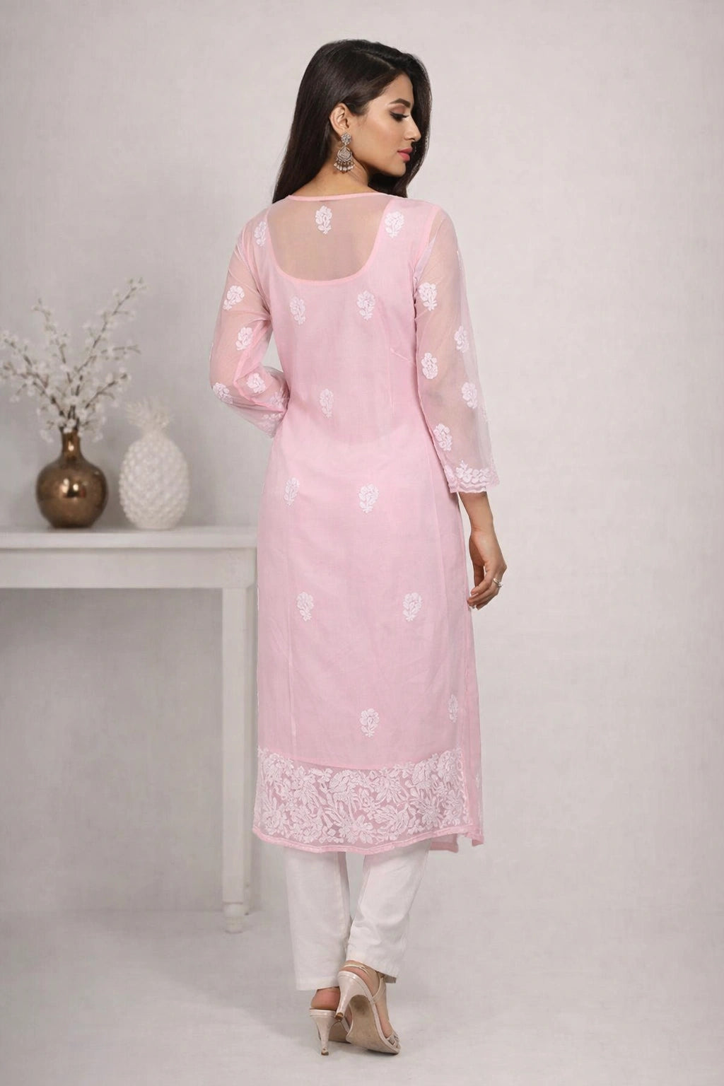 Woman wearing a chikan light pink kurta with white embroidery on a plain background